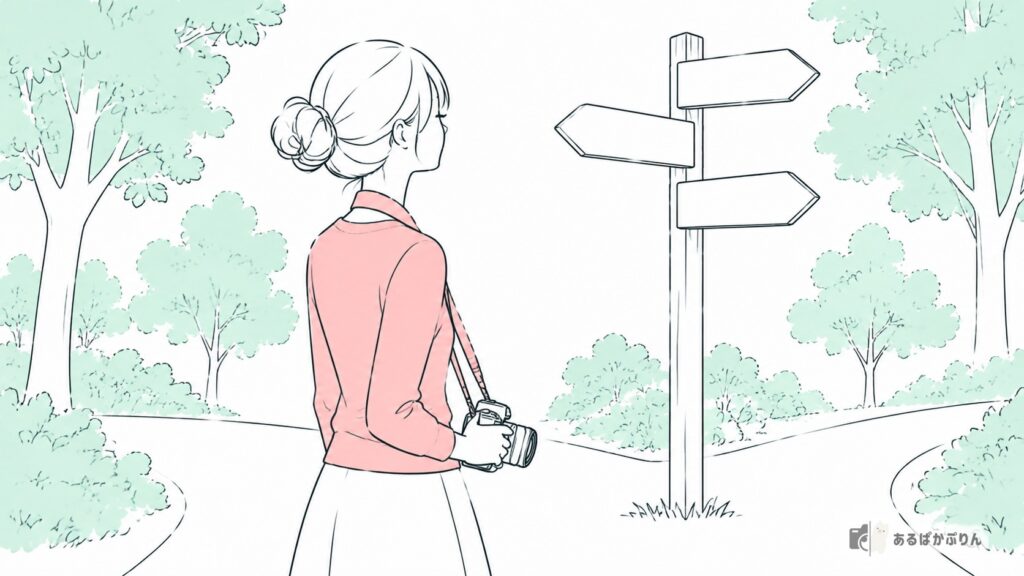 カメラを下げて分かれ道の道しるべを見る女性